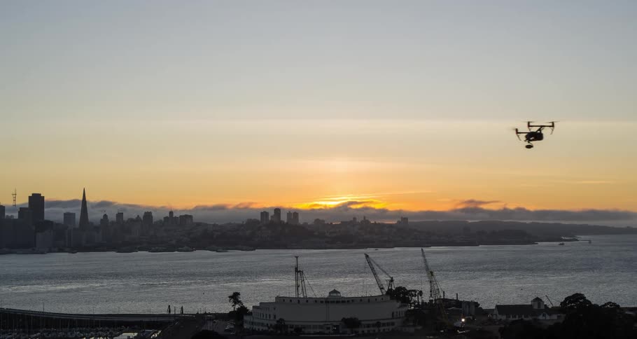 A drone flies over a waterfront area located near a metropolitan city