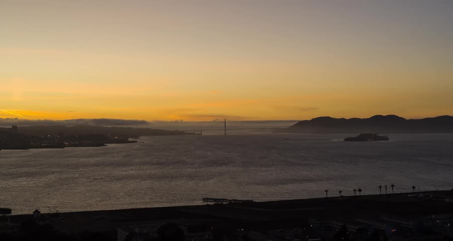 Coastal landscape at dusk with calm sea and mountains on the horizon