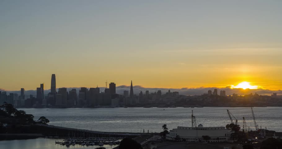 Towers and skyscrapers on the skyline along the metropolitan coast as the sun glows on the horizon