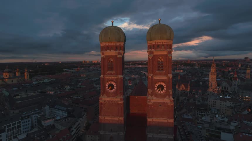 Aerial of twin clock towers in a metropolitan city skyline at sunset