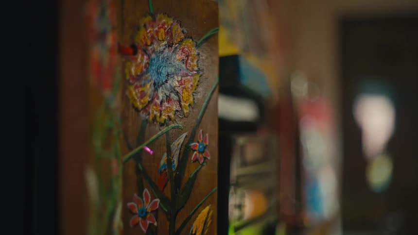 A tapestry has flowers embroidered on it next to a cabinet