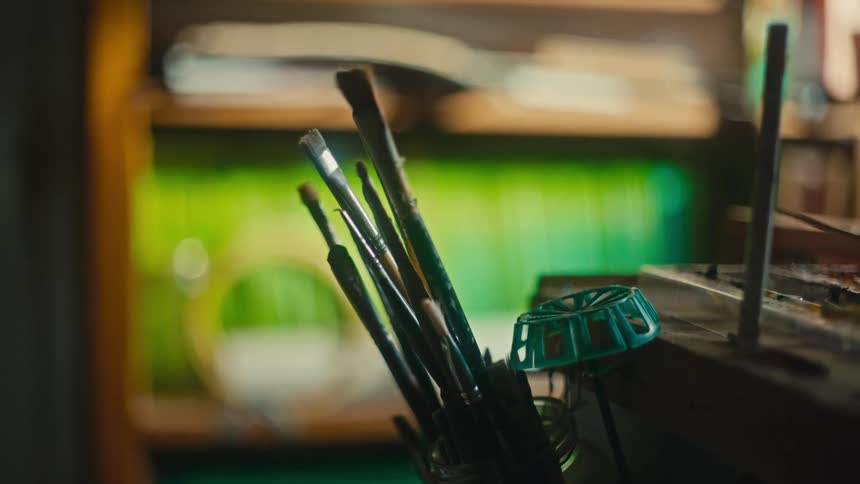 Paintbrushes are in a can in a room full of shelves