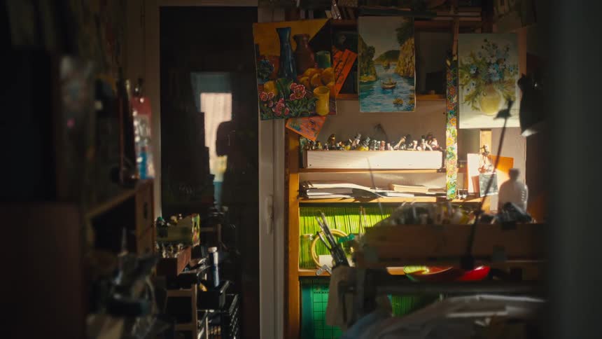 Studio lit by soft light with colorful paintings and scattered art supplies
