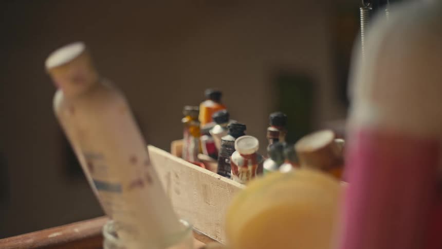 A wooden container holds several small tubes of paint