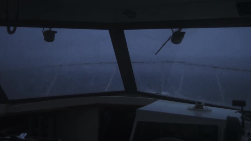 Thick fog blankets the sea seen from inside a boat cabin