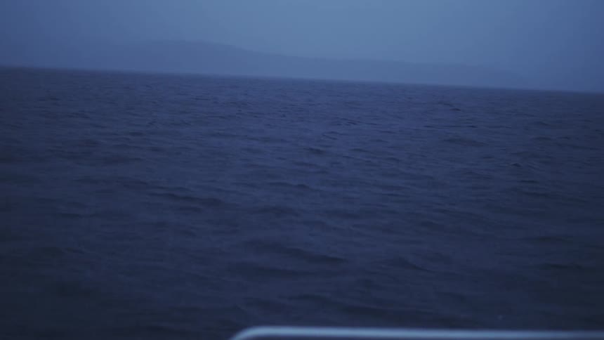 Distant horizon rises above the blue sea wrapped in soft mist