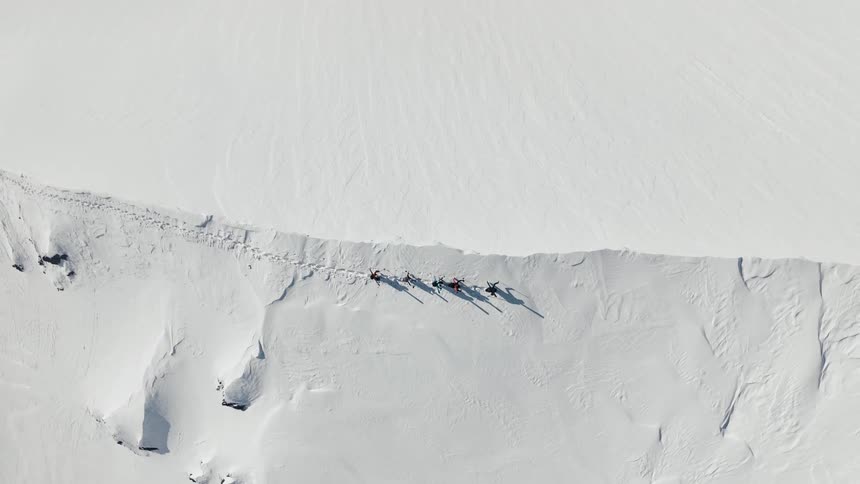 A group of people is cross country skiing across the ridge of a mountain