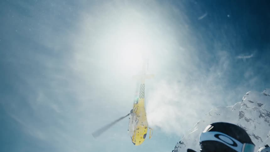 A yellow helicopter taking off in a mountain range