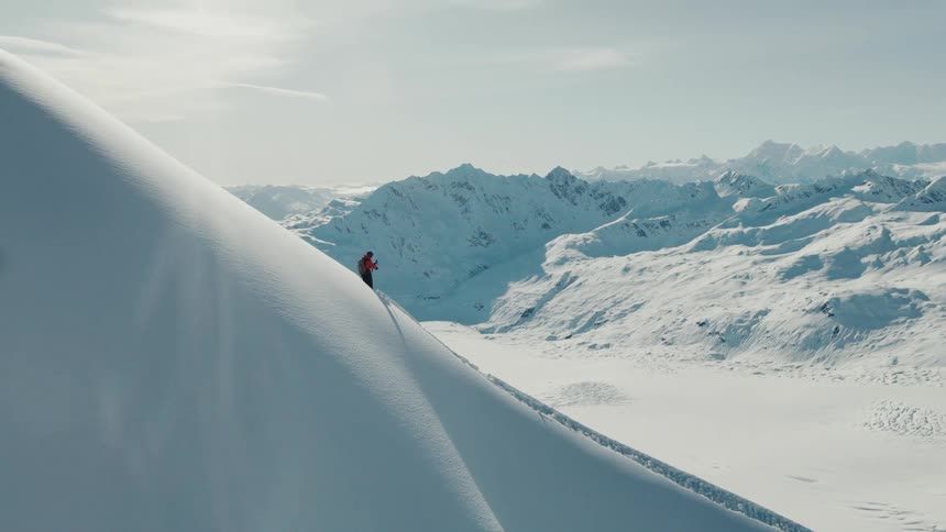 Climber ascends a steep snowcovered slope under bright sunlight