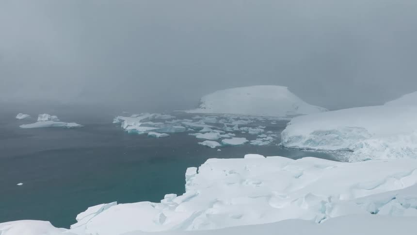 Ice blocks spread across the sea under dense fog