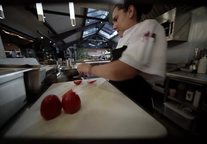 Line cook cutting tomatoes on a cutting board