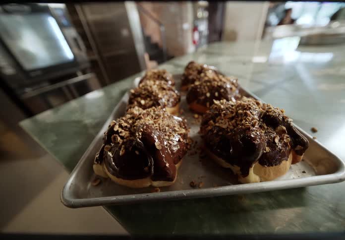 Breads topped with chocolate and nuts arranged on a baking tray