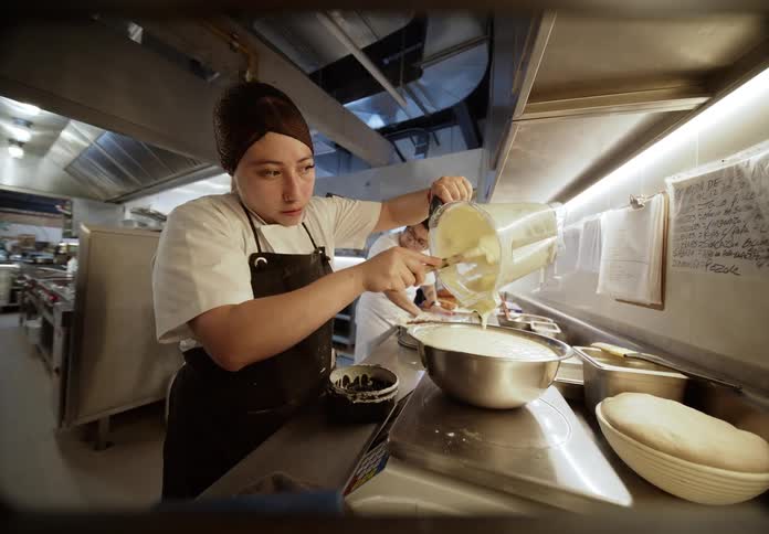 A woman making food in a commercial kitchen