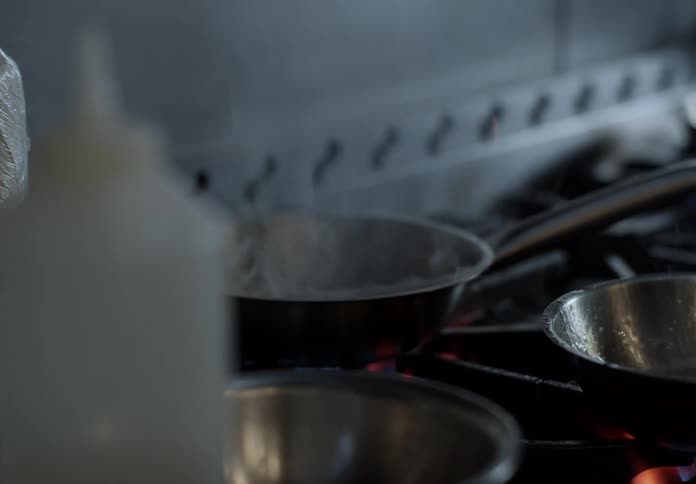 High flames rising from a frying pan during cooking on the stove