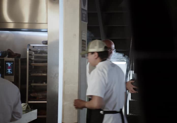 Chef holding a plate amid steam in the kitchen