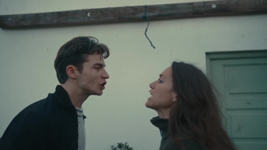 Man and woman arguing with intense gestures in front of a lightcolored wall