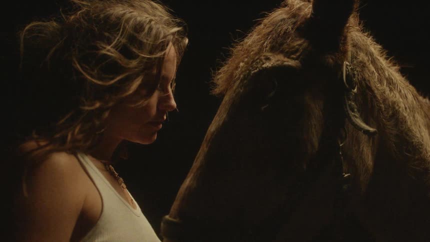 Woman standing next to her horse as she watches it move