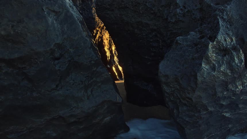 Water flows in a cave with light shining into the ravine