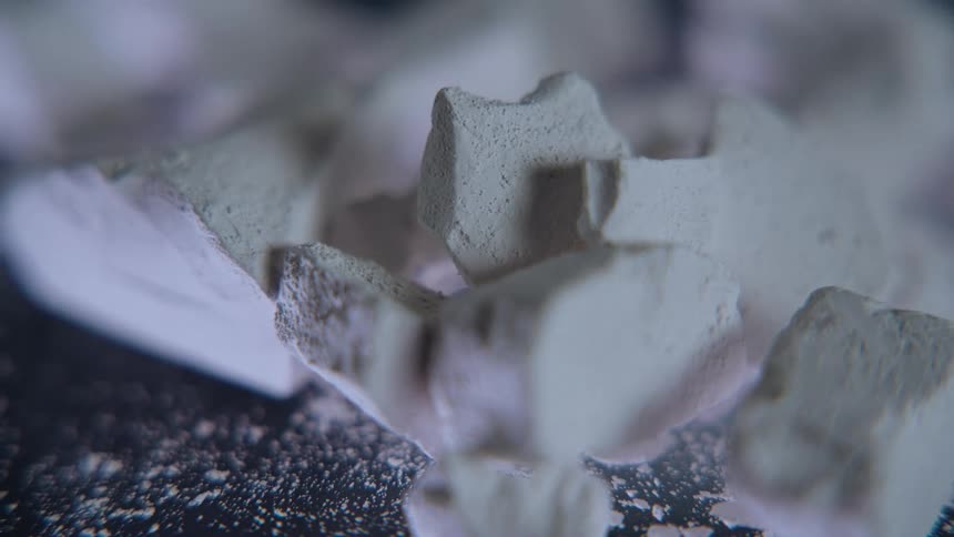 Broken pieces of white minerals on a dark surface