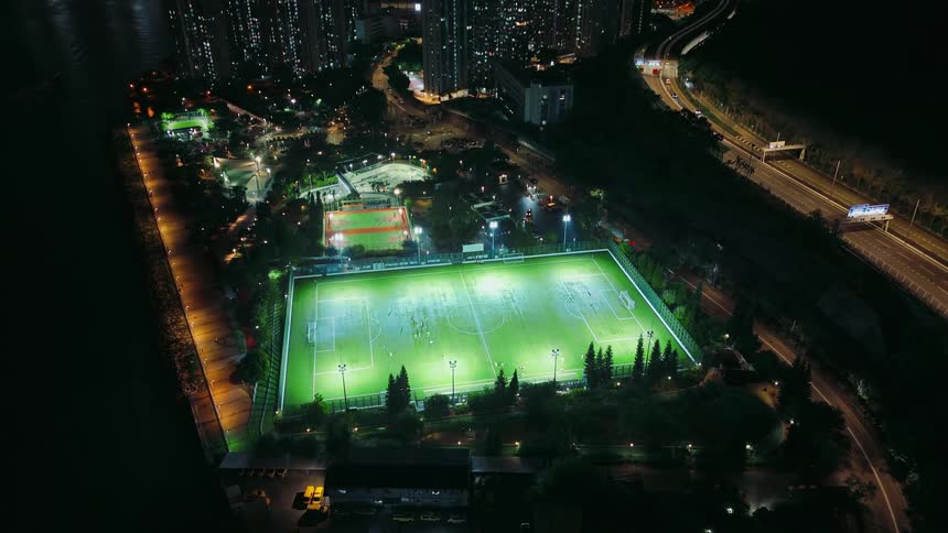 A large arena is lit up for a game at night in a city