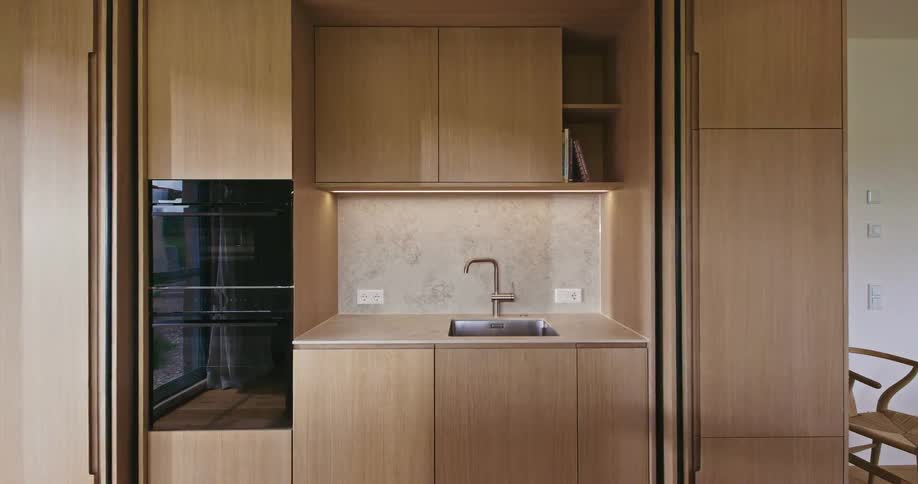 View of a kitchen inside a house with a chair next to the wall and an oven next to the counter and sink