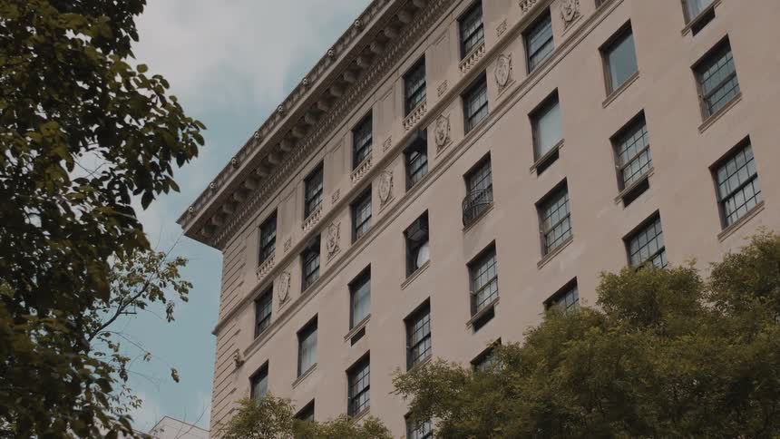 Classic urban building faade surrounded by trees under a clear sky