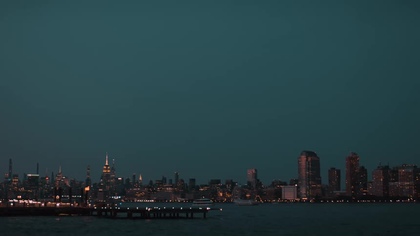 City skyline illuminated reflects lights over the water at dusk