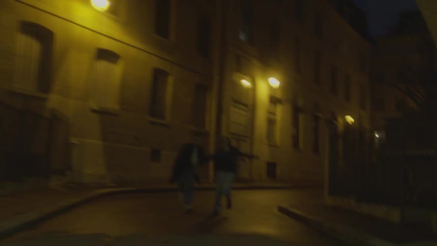 A man and woman are running down a city street at night