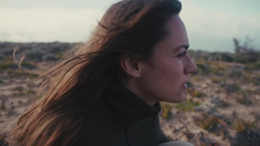 Woman gazes at the horizon with a contemplative expression under the winds breeze