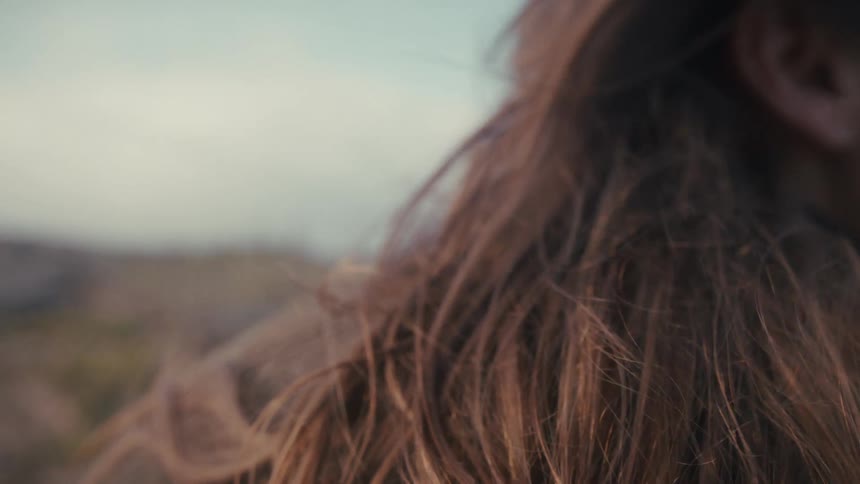 Wind moves her hair as she looks at the landscape ahead