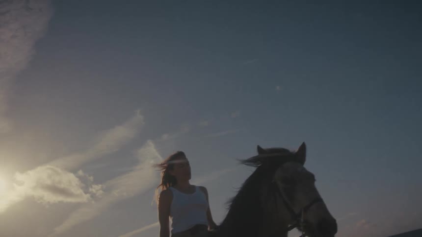 Woman rides by the seaside under the blue evening sky