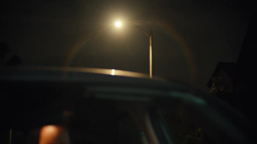 A woman sitting in a car under a street light