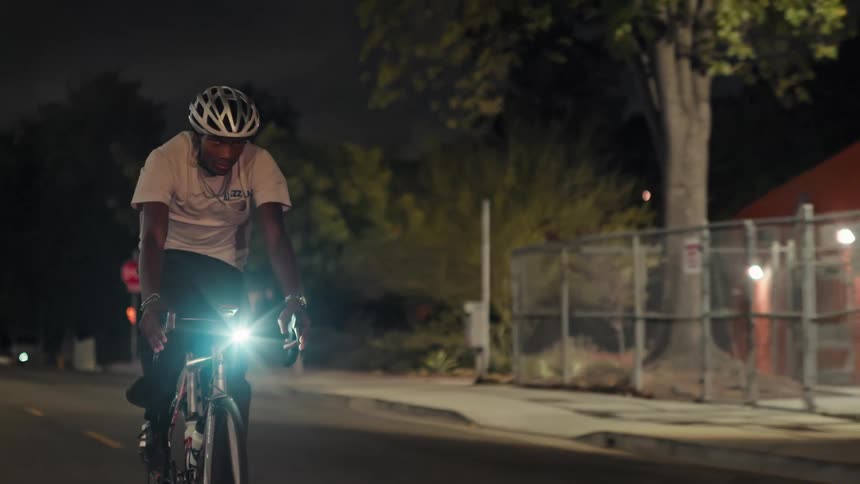 A man riding a bicycle in a city at night