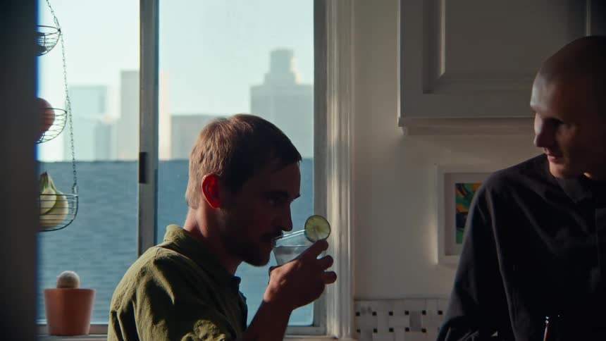 Two men talk in the kitchen lit by the afternoon sun