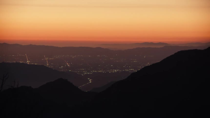 A view from mountains of the sun setting over a city