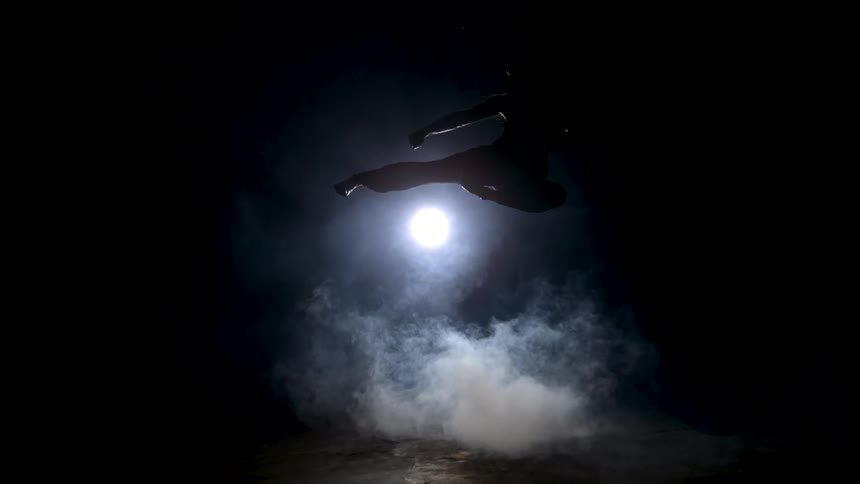 A man doing a flying kick at night