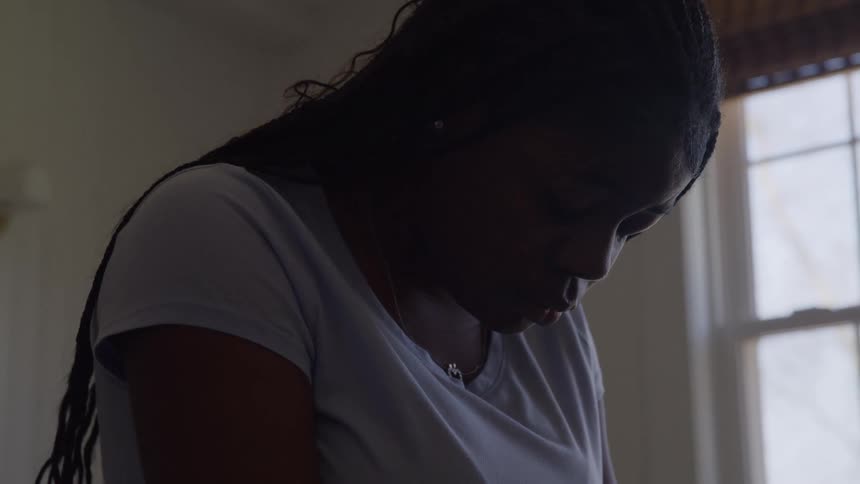 Woman stands in silence before the light coming through the window