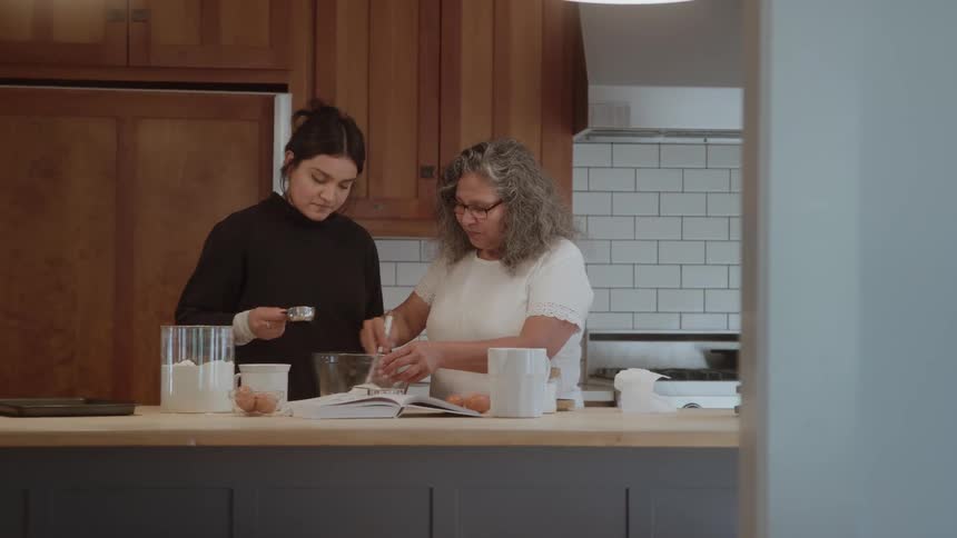 Two women prepare a recipe together in the kitchen