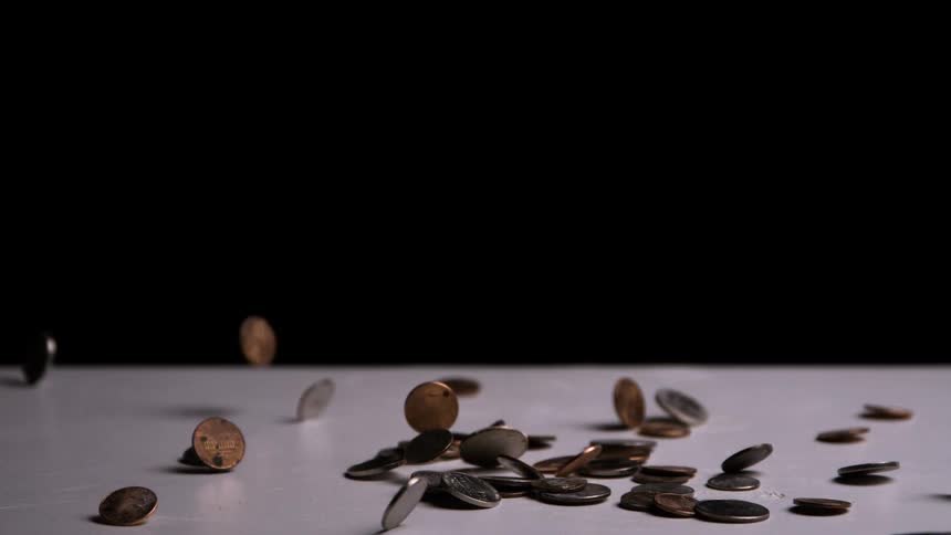 Coins fall and scatter across a light surface