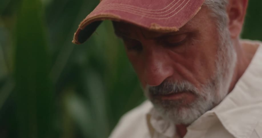 Man in a cap looking down with a serious expression
