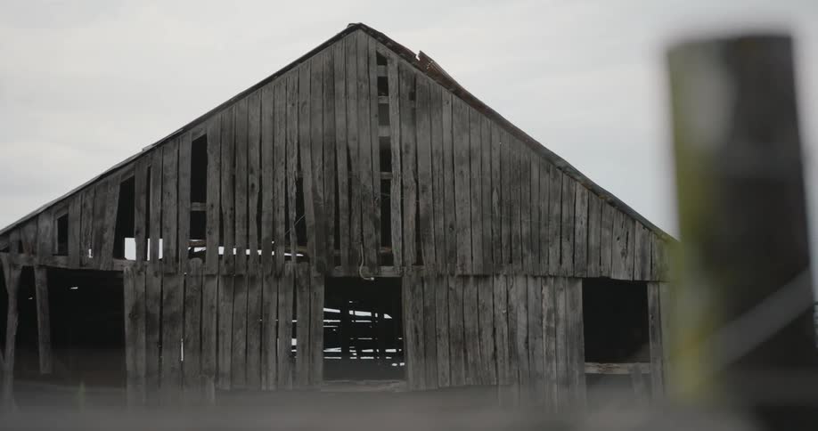 An old wooden barn is missing boards and is in disrepair