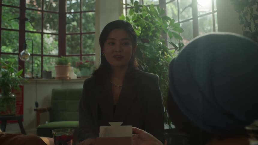 Two women sit indoors while having a friendly conversation