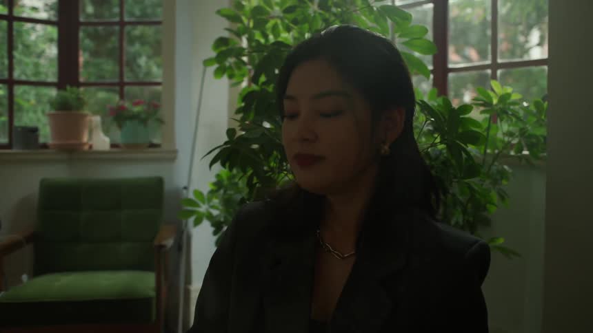 A woman tilts her head back playfully while eating berries in a bright living room