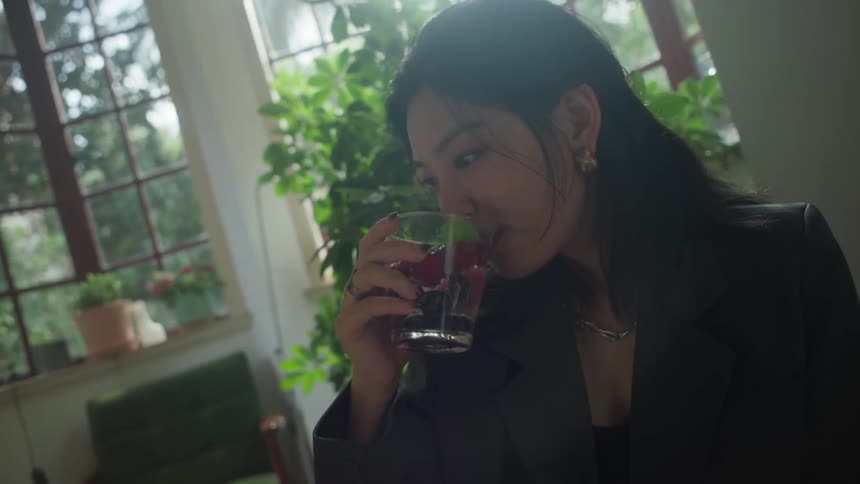 Woman drinking a fruitinfused beverage near the bright window