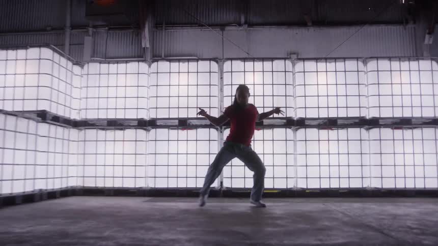 Man dancing in front of a wall of windows in a building