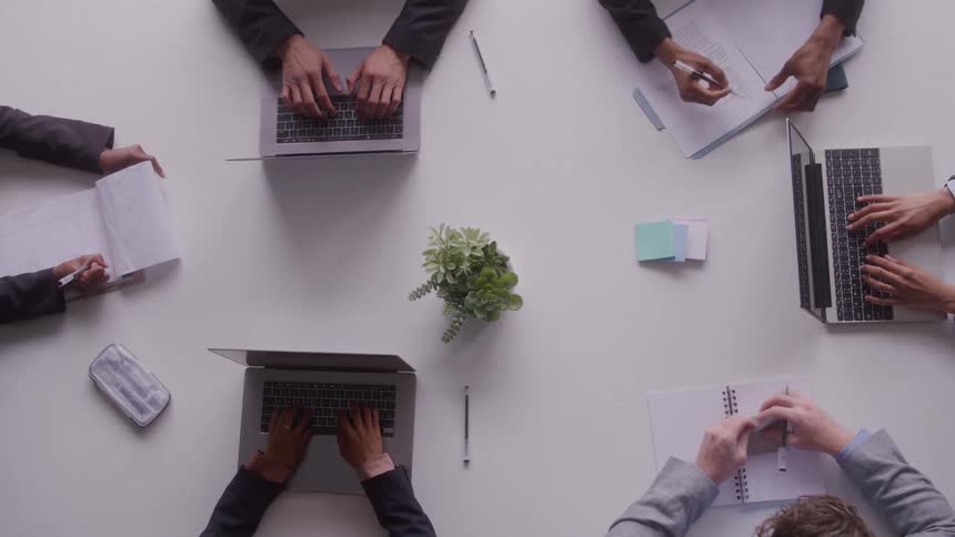 Workers type on their laptops and write in the office