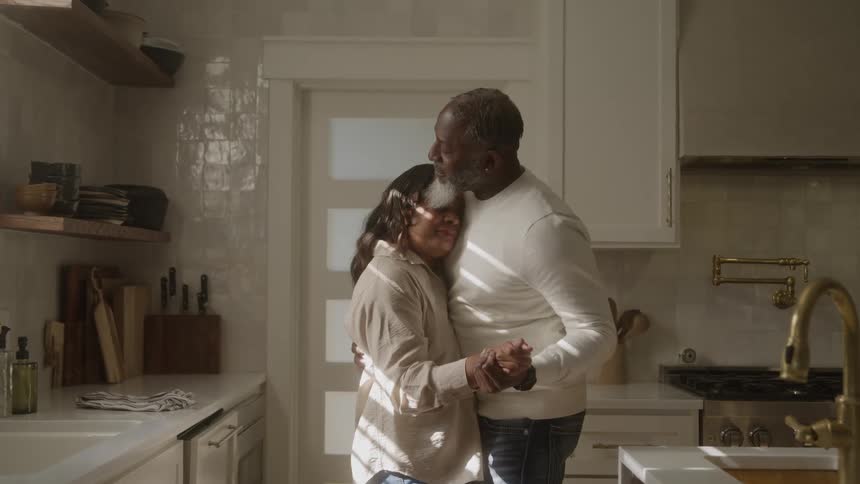 Couple embraces while slow dancing in the sunlit kitchen