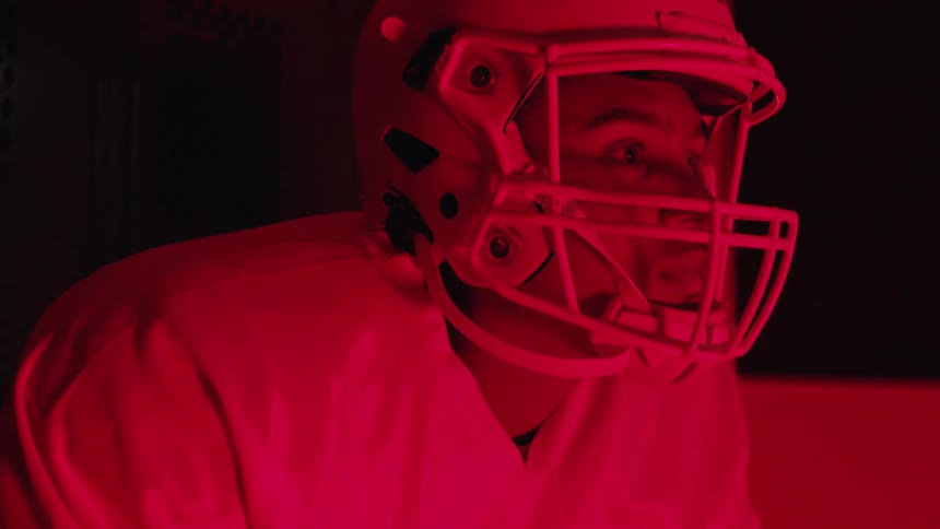 American football player looks ahead under intense red lighting