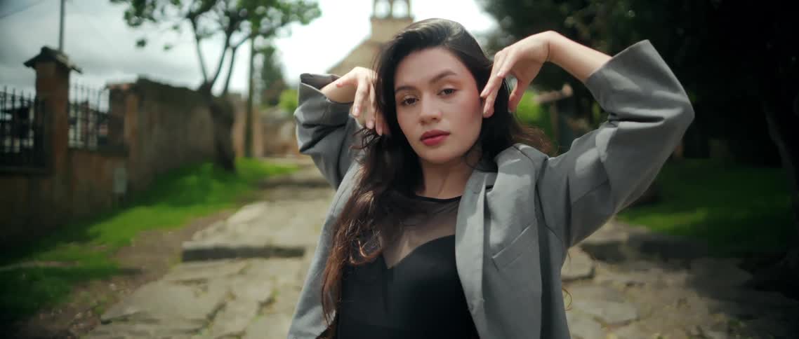 Woman lifts her arms while dancing on a stone pathway outdoors