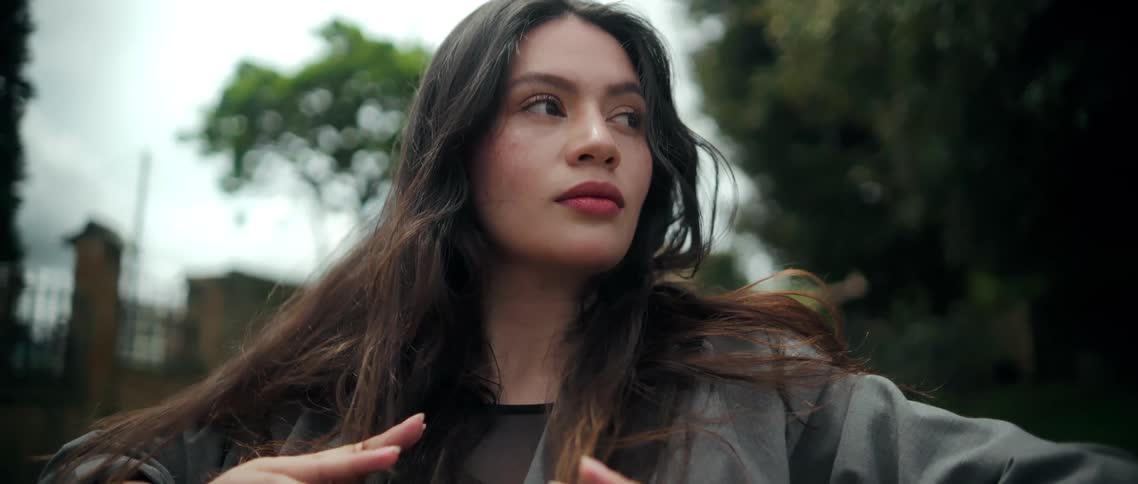 Woman moves her hands in front of her body while looking to the side with a focused expression